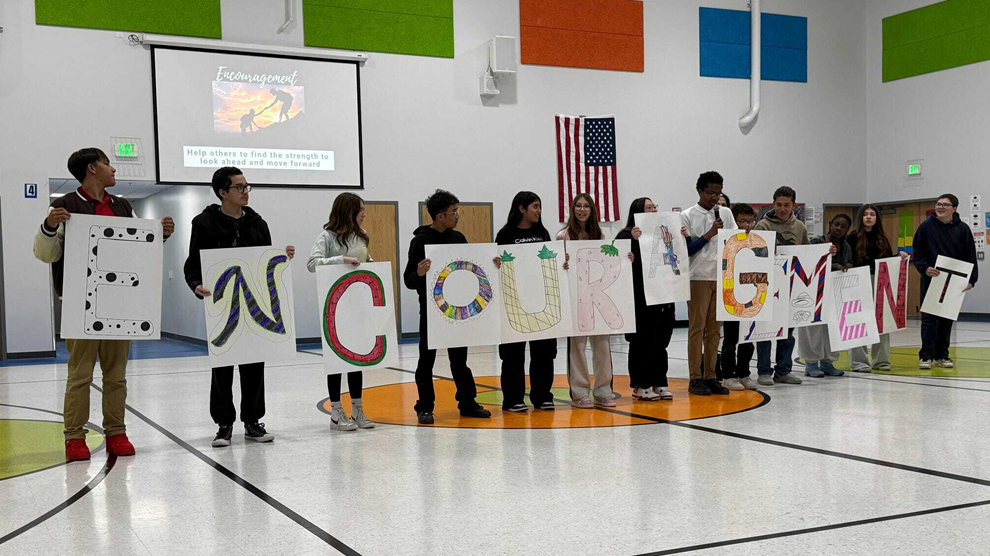 Students standing holding a sign spelling encouragement