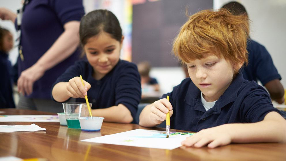 Two students smiling in front of their classroom lockers