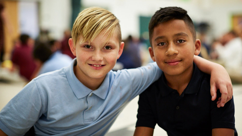 Two students smiling in front of their classroom lockers