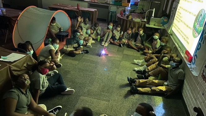 Students in a circle around an indoor "campfire"