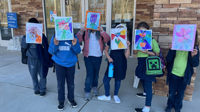 Students holding up their art.