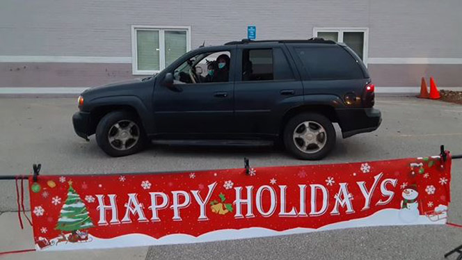 A vehicle in front of a poster that reads Happy Holidays.