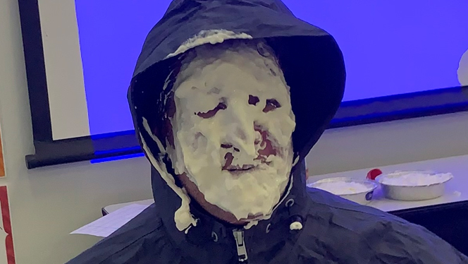 An adult with pie on their face.