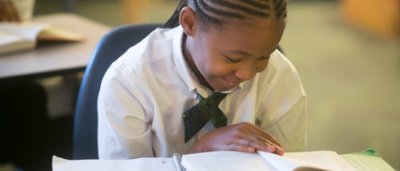 Burton Glen Charter Academy, Y5-8 School in Burton, MI: little girl reading a book and laughing.
