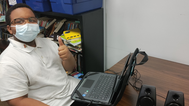 Student giving a thumbs up at his computer