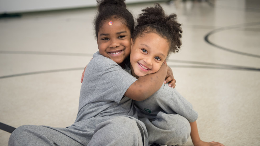 Two students smiling in front of their classroom lockers