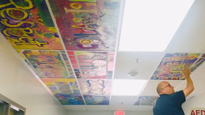 Student paintings being added as ceiling tiles.