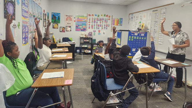 Students raising hand in classroom.