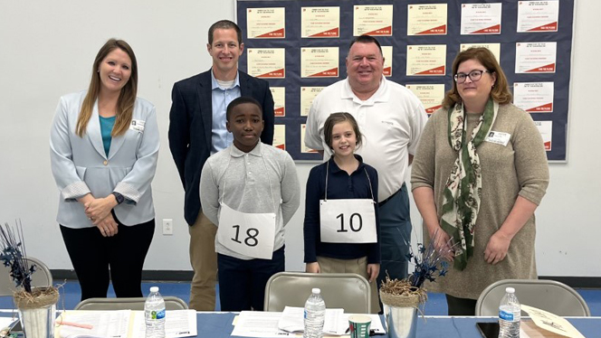 Spelling bee judges standing next to the winners.