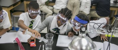 K-8 School in Detroit: Students wearing goggles, doing science experiment.