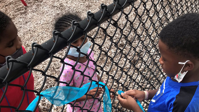 Children talking through a chain link fence.