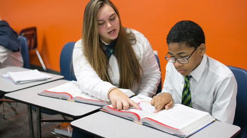 Two students smiling in front of their classroom lockers