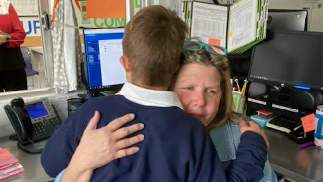Teacher hugging student.