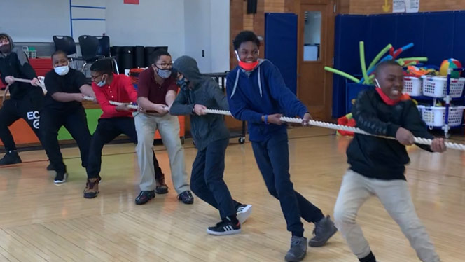 Students smiling while playing tug-of-war.