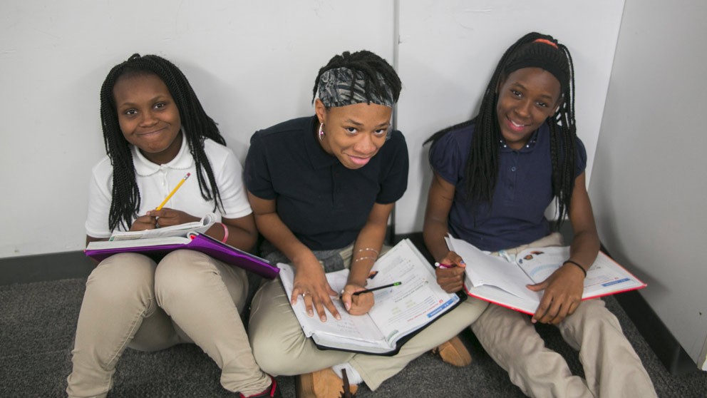 Two students smiling in front of their classroom lockers