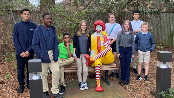 Children gathered around a Ronald McDonald statue.