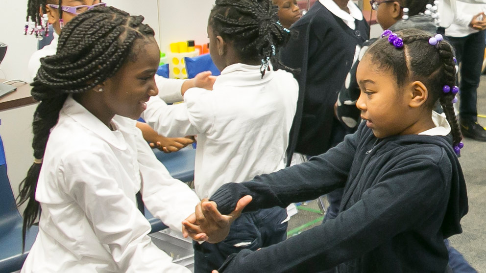 Two students smiling in front of their classroom lockers