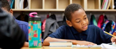Atlanta Heights Charter School, K-8 School in Atlanta, GA: boy sitting at desk looking at paper with pencil in hand.